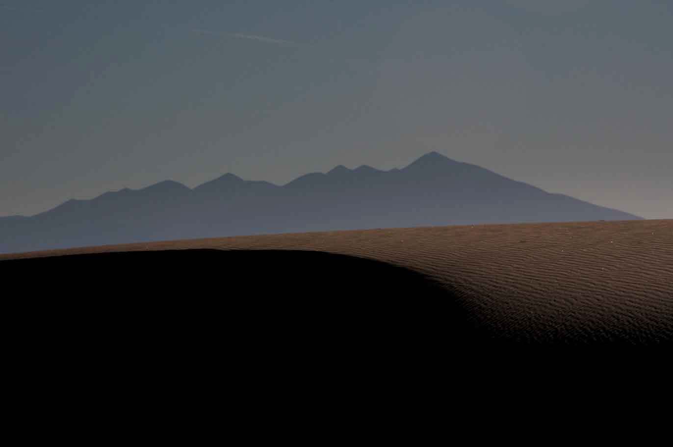 Sand dune in the Arizona high desert, on the Navajo Nation with the San Francisco Peaks in the distance