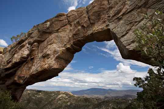 Looking through Rocky Arch in the Catalina Mts., Arizona. In the distance, about 20 miles to the southeast, are the Rincon Mts.